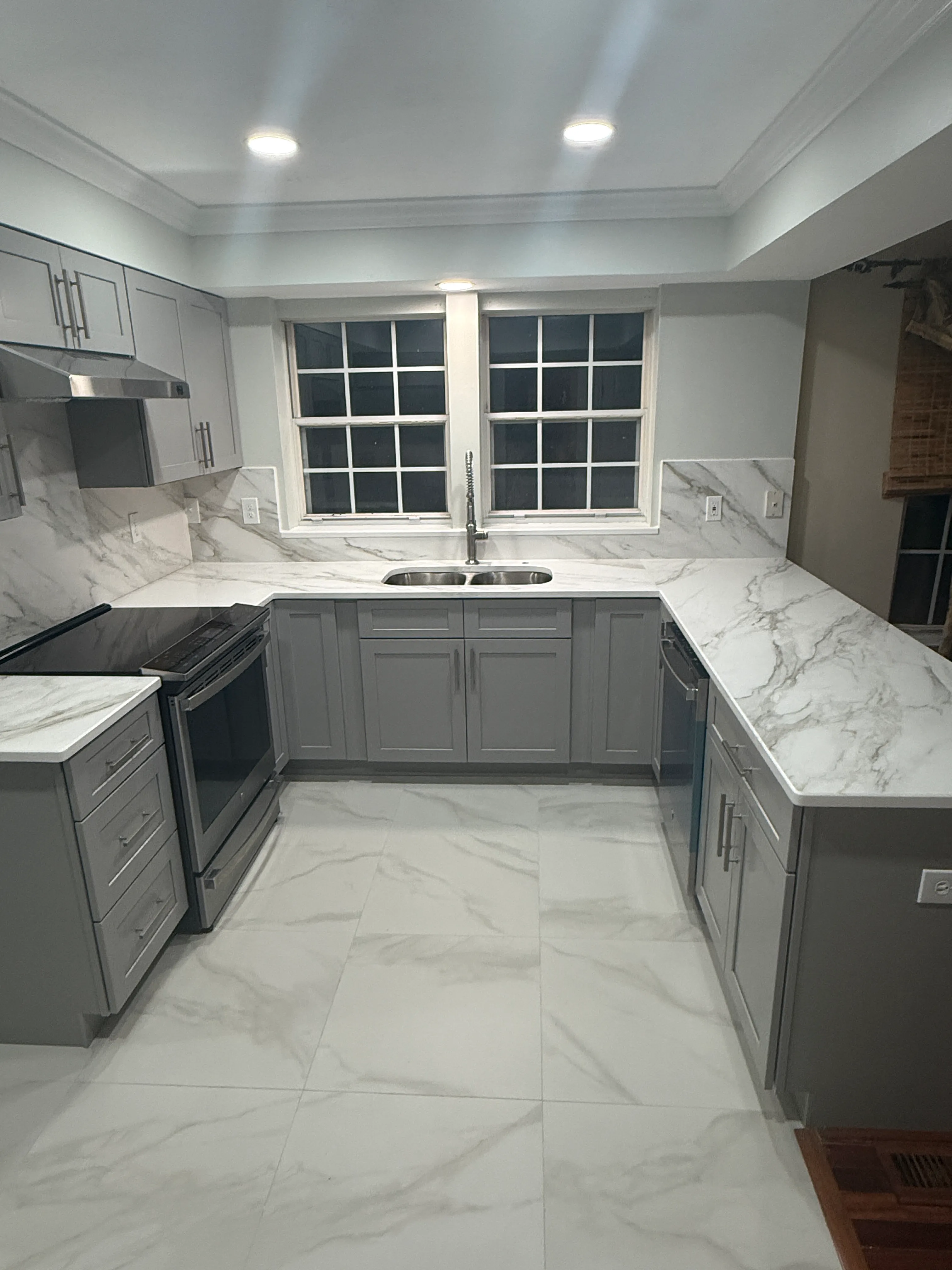 Kitchen with gray cabinets, a double sink, and light counters